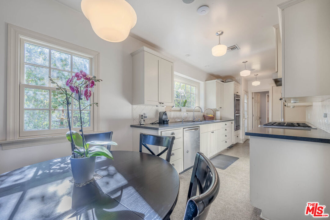 9038 Cresta Drive Los Angeles, CA 90035 - Photo 7 of 23 a kitchen with granite countertop a sink a counter space dining table and a chandelier