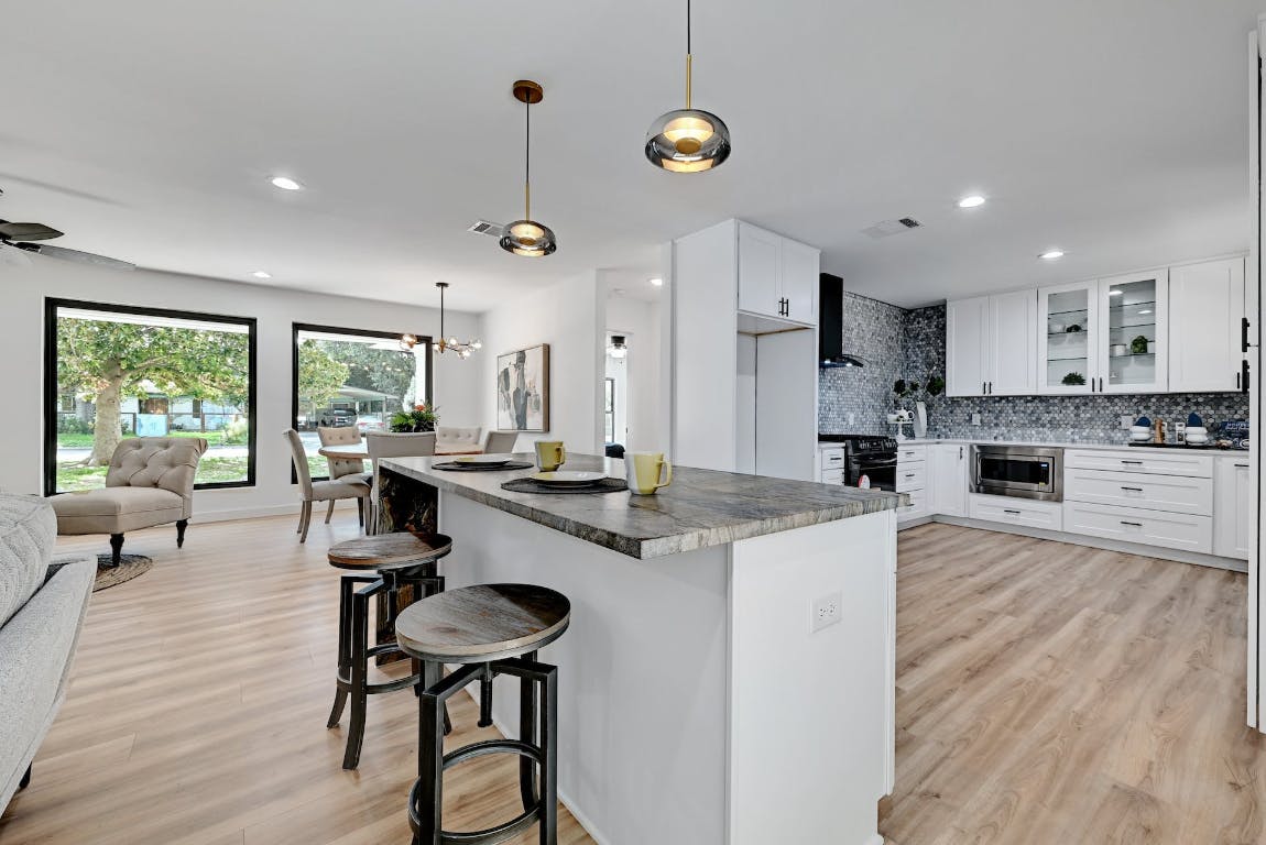 4604 Nevada Path Austin, TX 78745 - Photo 4 of 10 a open kitchen with stainless steel appliances granite countertop a stove a refrigerator a kitchen island a dining table and chairs with wooden floor