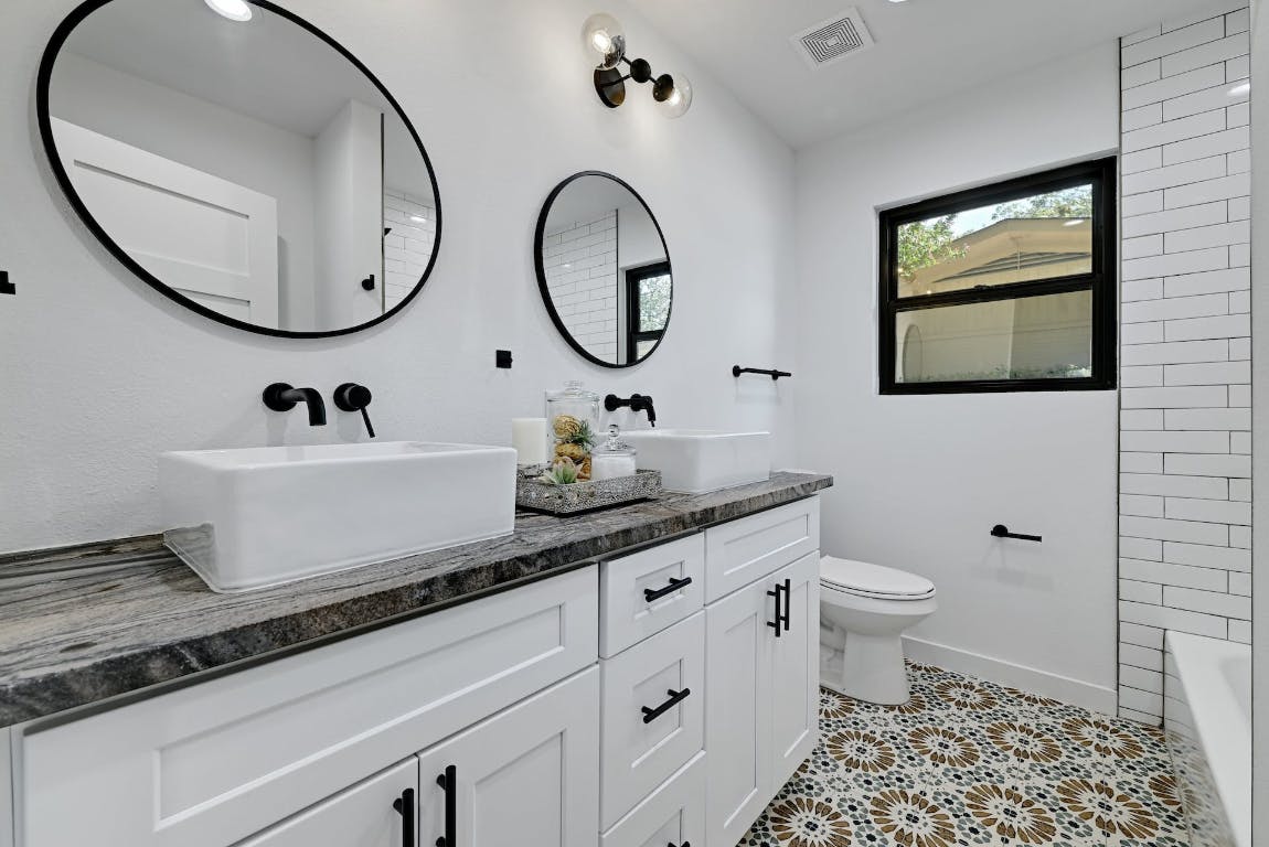 4604 Nevada Path Austin, TX 78745 - Photo 8 of 10 a bathroom with a granite countertop toilet a sink and a mirror