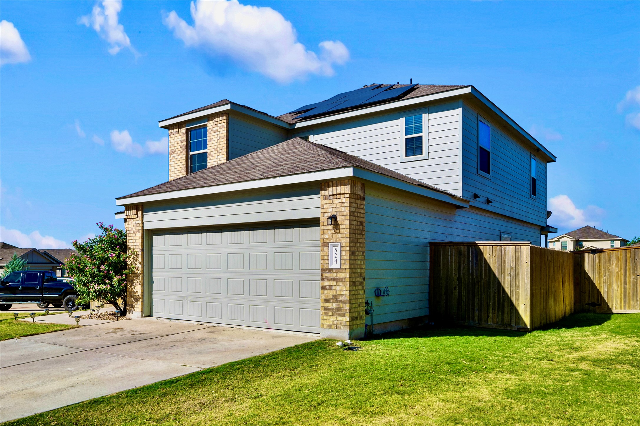 524 Circle Way, Unit 12F Jarrell, TX 76537 - Photo 2 of 34 View of side of home featuring solar panels, driveway, an attached garage, and roof with shingles