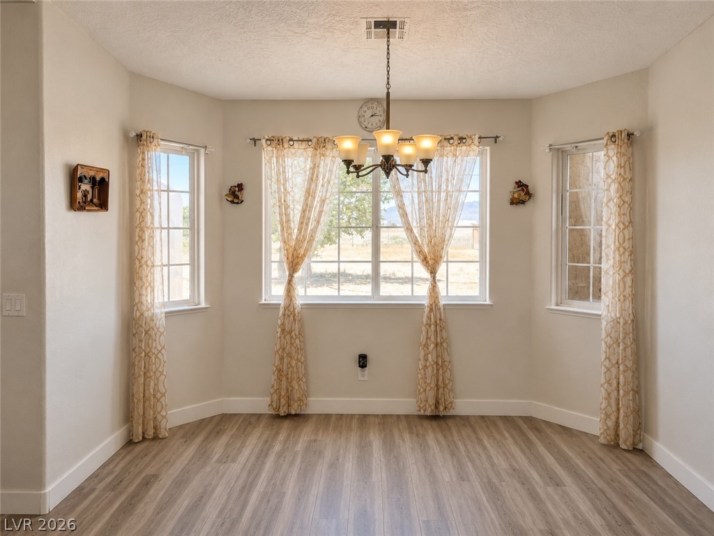 200 East Gamebird Road Pahrump, NV 89048 - Photo 10 of 23 A graceful dining area, well-lit by multiple windows, showcases durable flooring and an elegant chandelier.