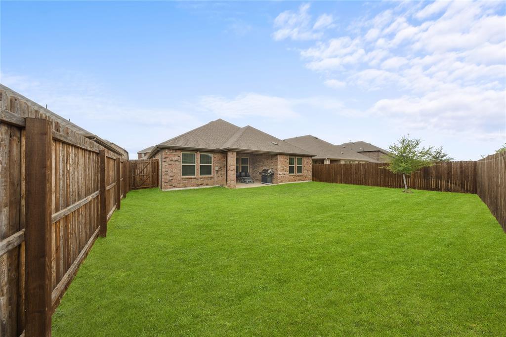 9805 Quail Pointe Road Aubrey, TX 76227 - Photo 24 of 38 Expansive rear yard featuring a large grass area, wood privacy fencing, and a covered patio