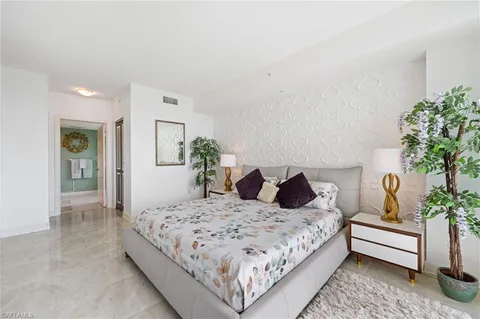 a bedroom with a large bed and a potted plant