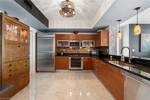 a kitchen with stainless steel appliances kitchen island granite countertop a stove refrigerator and cabinets