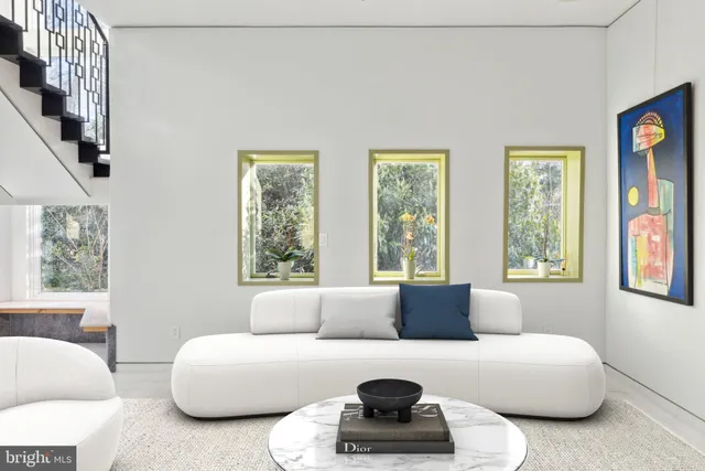 a living room with furniture and a potted plant next to a window