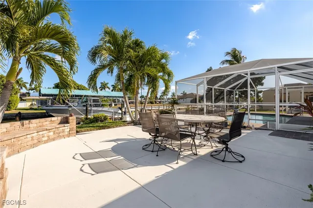 a view of a patio with a table and chairs under an umbrella with palm trees