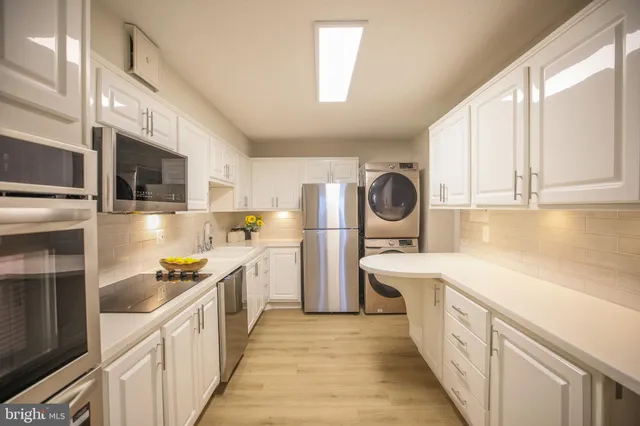 a kitchen with stainless steel appliances a sink a stove a refrigerator cabinets and a window