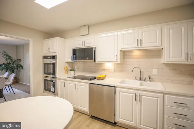 a kitchen with a sink white cabinets and stainless steel appliances