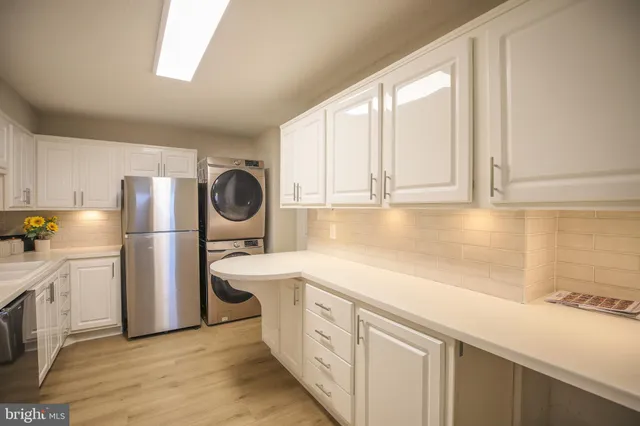 a kitchen with stainless steel appliances a refrigerator a sink a stove and white cabinets
