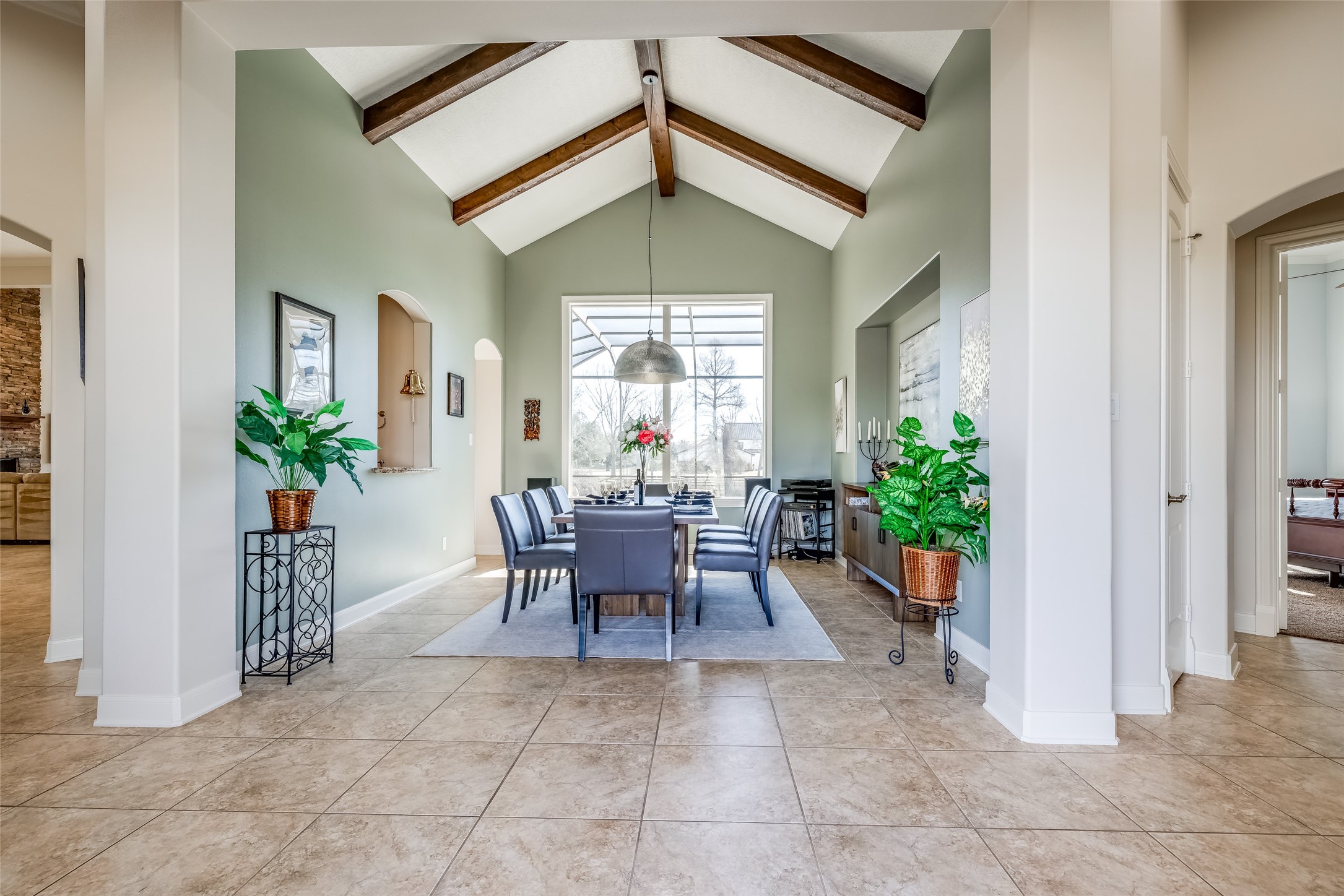31102 Lower Oxbow Trace Fulshear, TX 77441 - Photo 6 of 50 Beautiful large Dining Room with high ceiling, wooden ceiling beams, great views of pool & Oxbow Lake, tile floors, window through to wine room & bar, modern chandelier
