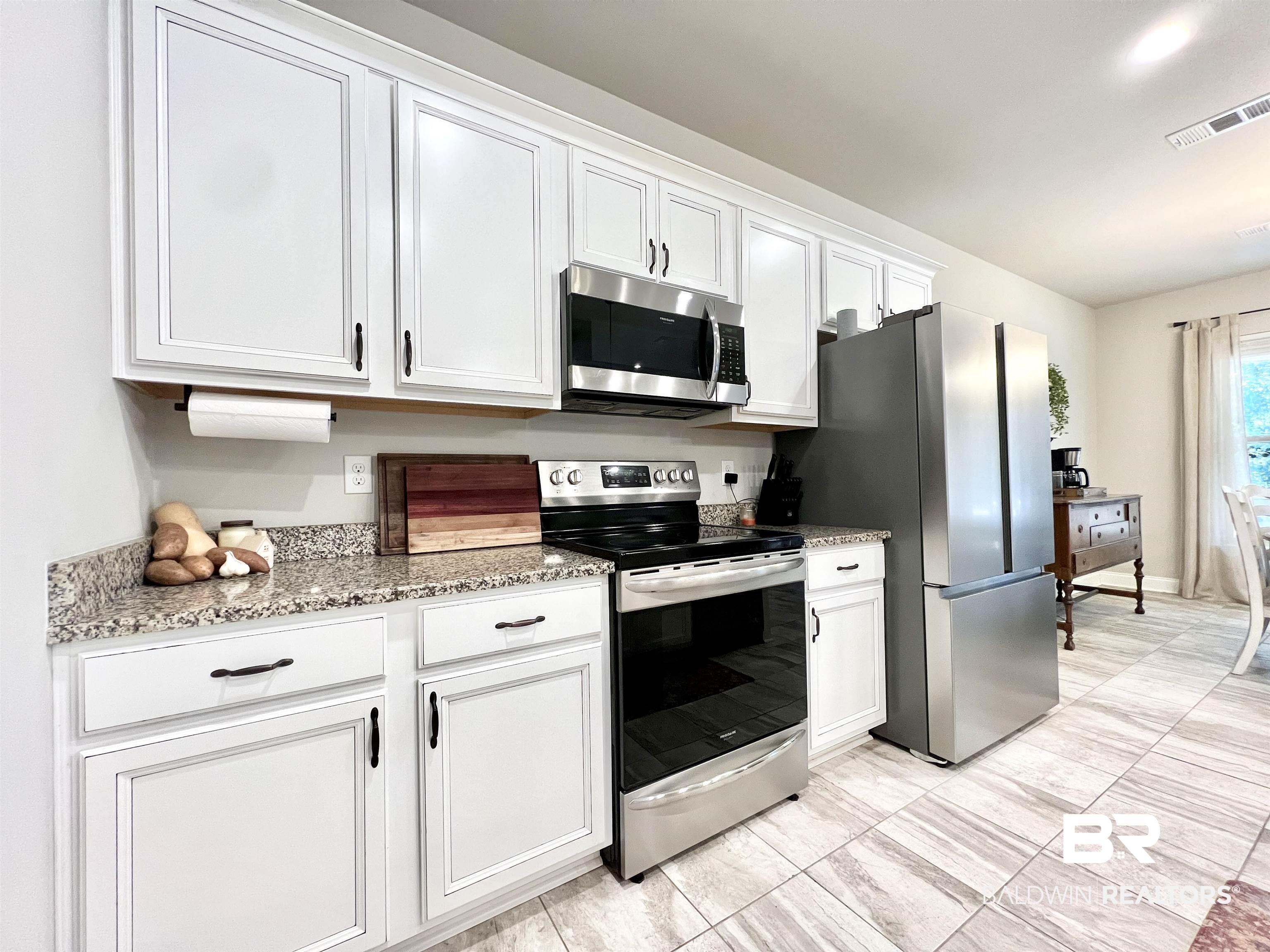 32290 Calder Court Daphne, AL 36527 - Photo 23 of 59 Kitchen with light stone countertops, white cabinets, and stainless steel appliances