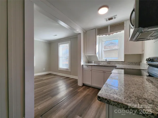 a kitchen with granite countertop wooden floors and stainless steel appliances