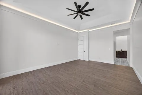 an empty room with wooden floor and ceiling fan