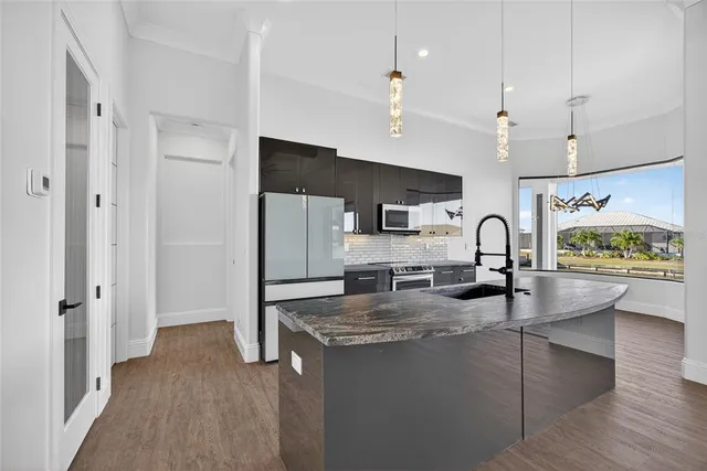 a kitchen with stainless steel appliances granite countertop a refrigerator a stove and white cabinets with wooden floor