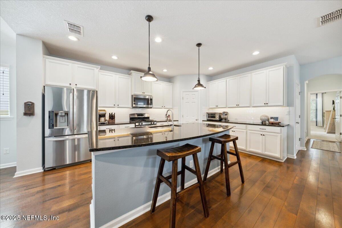 31 Skylar Lane Ponte Vedra, FL 32081 - Photo 4 of 32 a kitchen with stainless steel appliances kitchen island granite countertop a refrigerator a stove a oven a sink a island and chairs with wooden floor