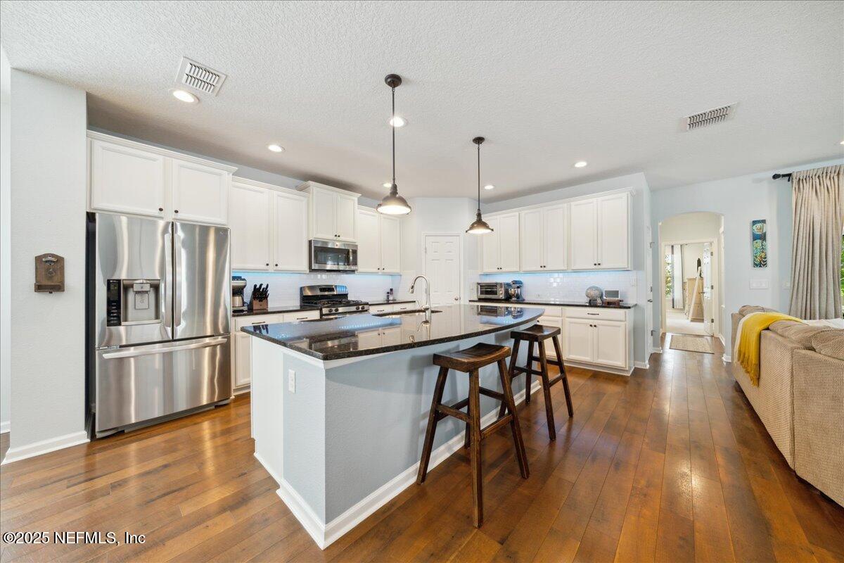 31 Skylar Lane Ponte Vedra, FL 32081 - Photo 7 of 32 a kitchen with stainless steel appliances kitchen island granite countertop a refrigerator a stove a sink a dining table and chairs with wooden floor
