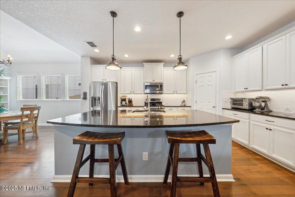 31 Skylar Lane Ponte Vedra, FL 32081 - Photo 10 of 32 a kitchen with stainless steel appliances kitchen island granite countertop a dining table chairs and white cabinets