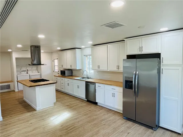 a large kitchen with a center island wooden floor and stainless steel appliances