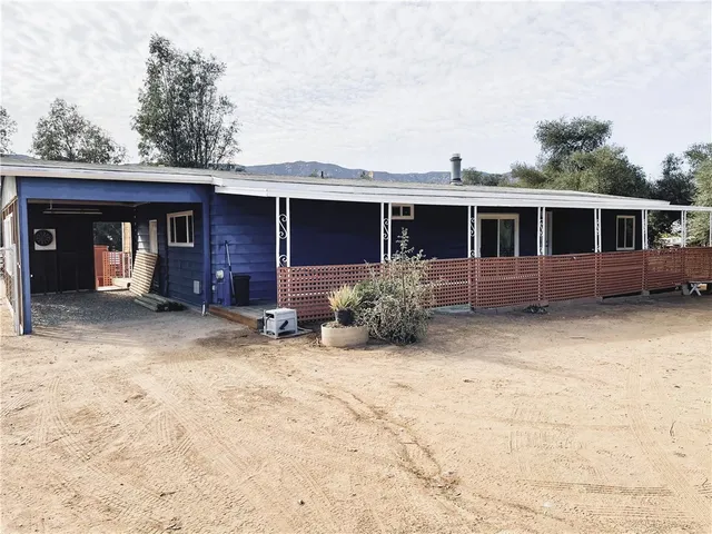 a view of house with backyard and trees in the background