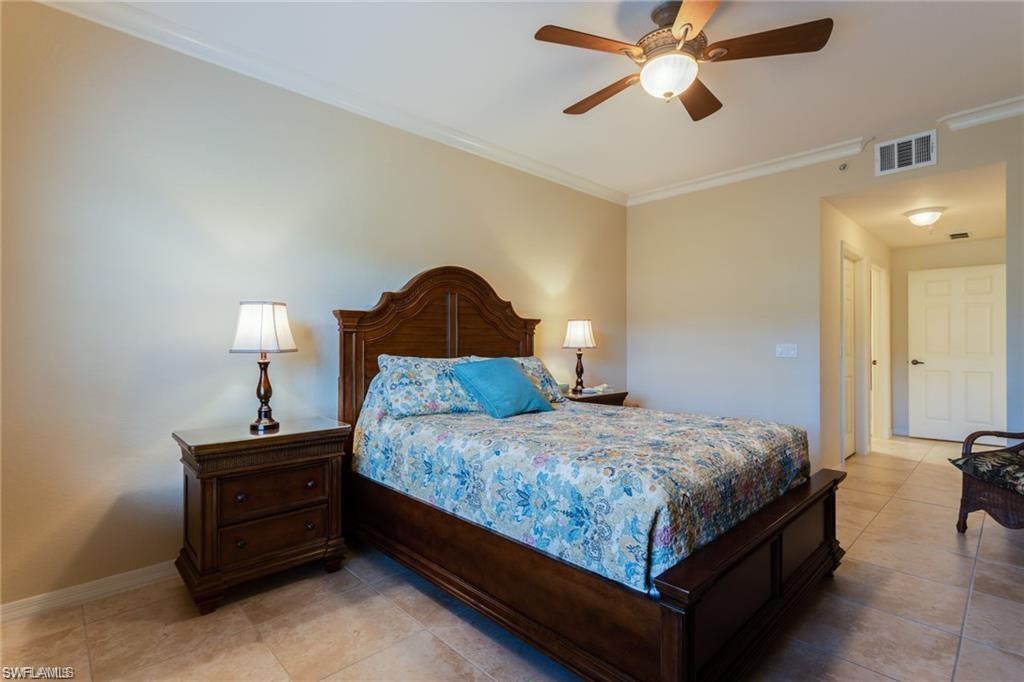20201 Estero Gardens Circle, Unit 104 Estero, FL 33928 - Photo 18 of 38 a bedroom with a bed and a chandelier