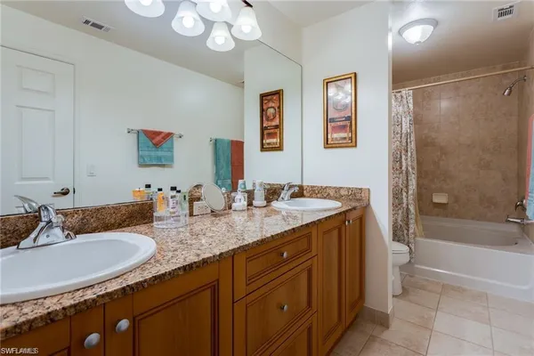 a bathroom with a granite countertop sink a toilet a mirror a bathtub and shower
