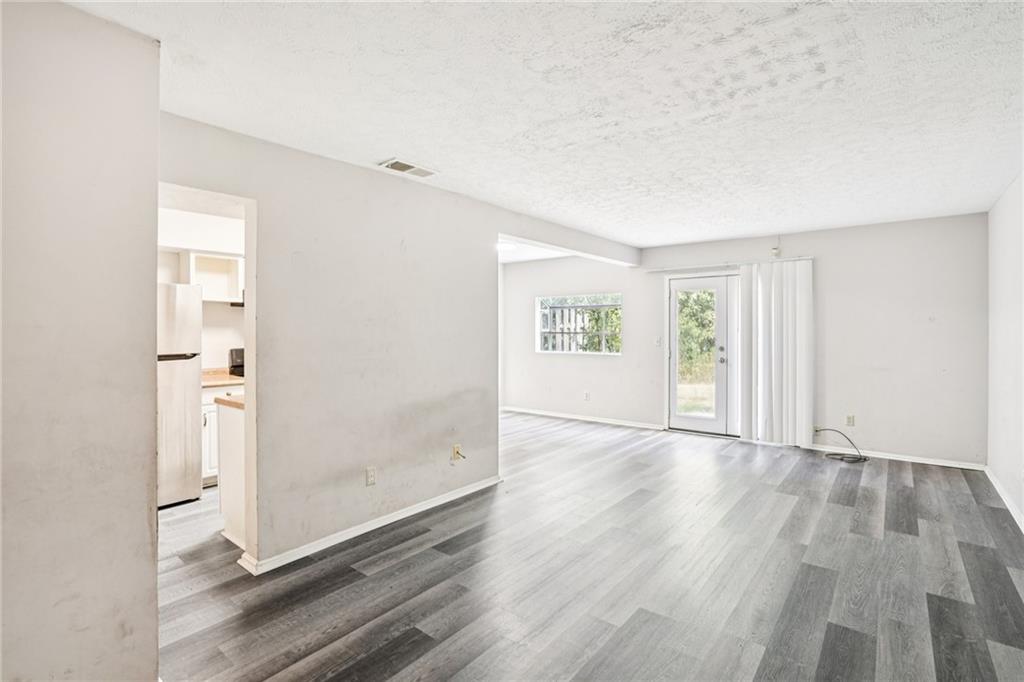 1608 Pine Tree Trail Atlanta, GA 30349 - Photo 3 of 17 an empty room with wooden floor and windows