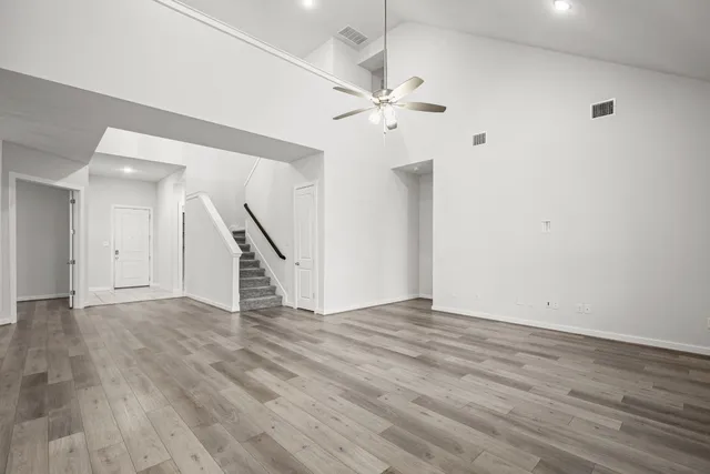 wooden floor in an empty room with a chandelier fan