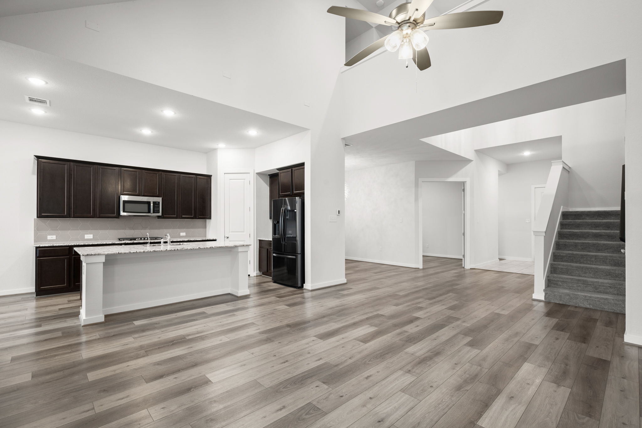 841 Spinnaker Loop Kyle, TX 78640 - Photo 39 of 40 Kitchen featuring open floor plan, black fridge with ice dispenser, dark brown cabinets, stainless steel microwave, and a center island with sink