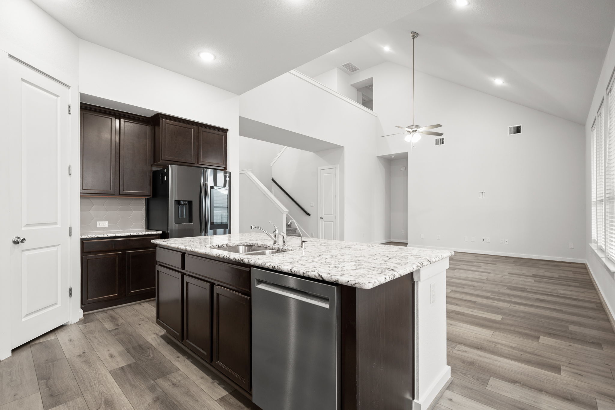 841 Spinnaker Loop Kyle, TX 78640 - Photo 40 of 40 Kitchen featuring dark brown cabinetry, appliances with stainless steel finishes, a kitchen island with sink, open floor plan, and light wood finished floors
