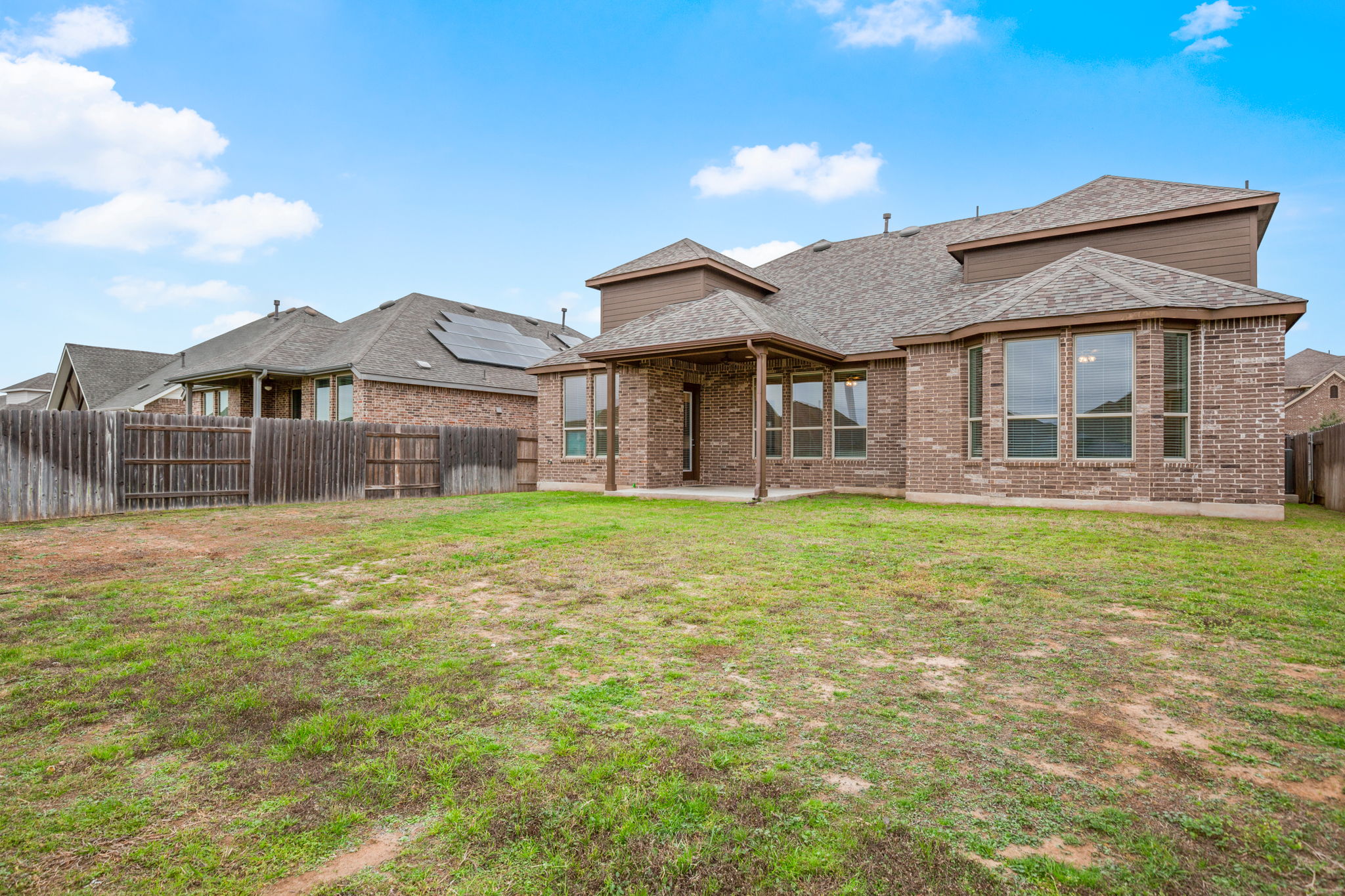 841 Spinnaker Loop Kyle, TX 78640 - Photo 38 of 40 Back of property with a patio area, a shingled roof, a fenced backyard, and brick siding