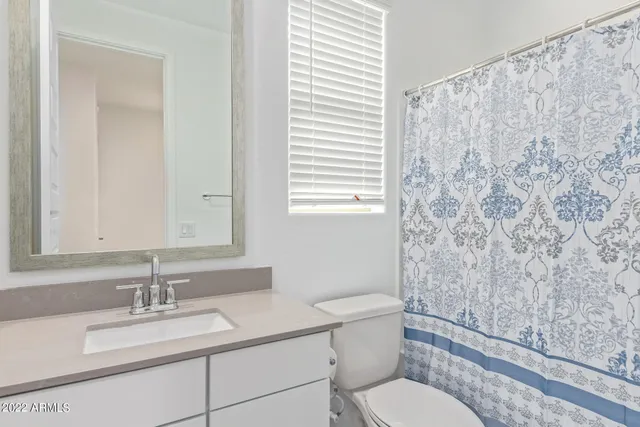 a bathroom with a granite countertop toilet sink and mirror