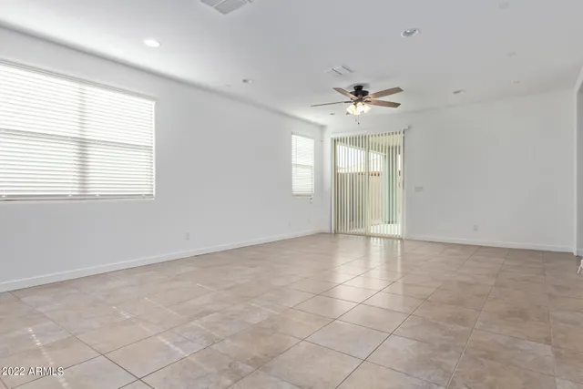 an empty room with windows and chandelier fan