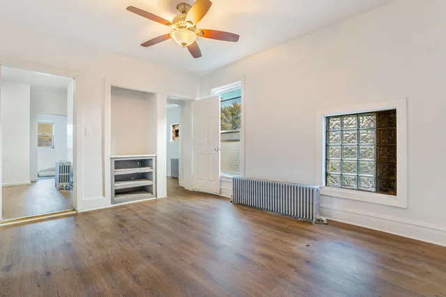an empty room with wooden floor closet and windows