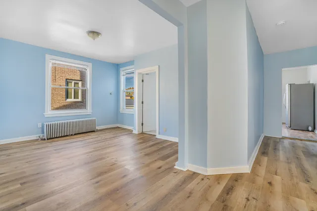 a view of an empty room with wooden floor and a window