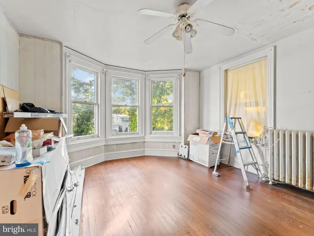 a view of a livingroom with furniture hardwood floor a ceiling fan and windows