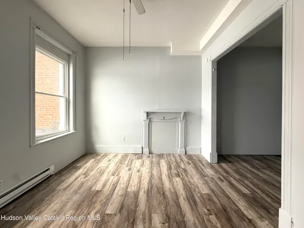 a view of empty room with wooden floor and fan