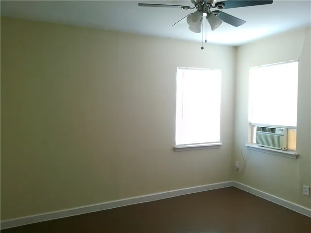 an empty room with a window and a fan
