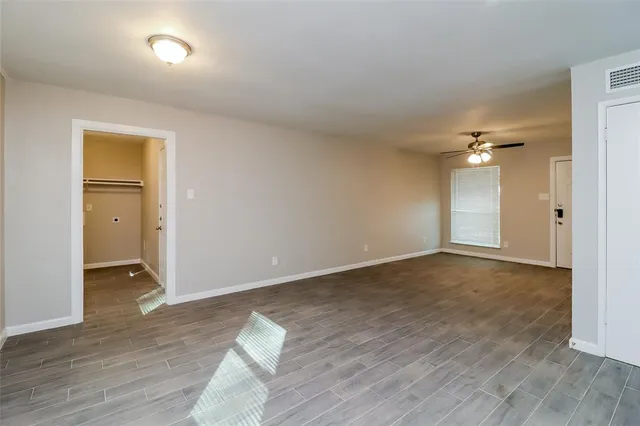 an empty room with wooden floor and a ceiling fan