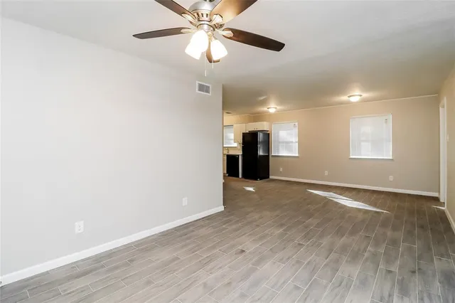 a view of an empty room with a window and wooden floor