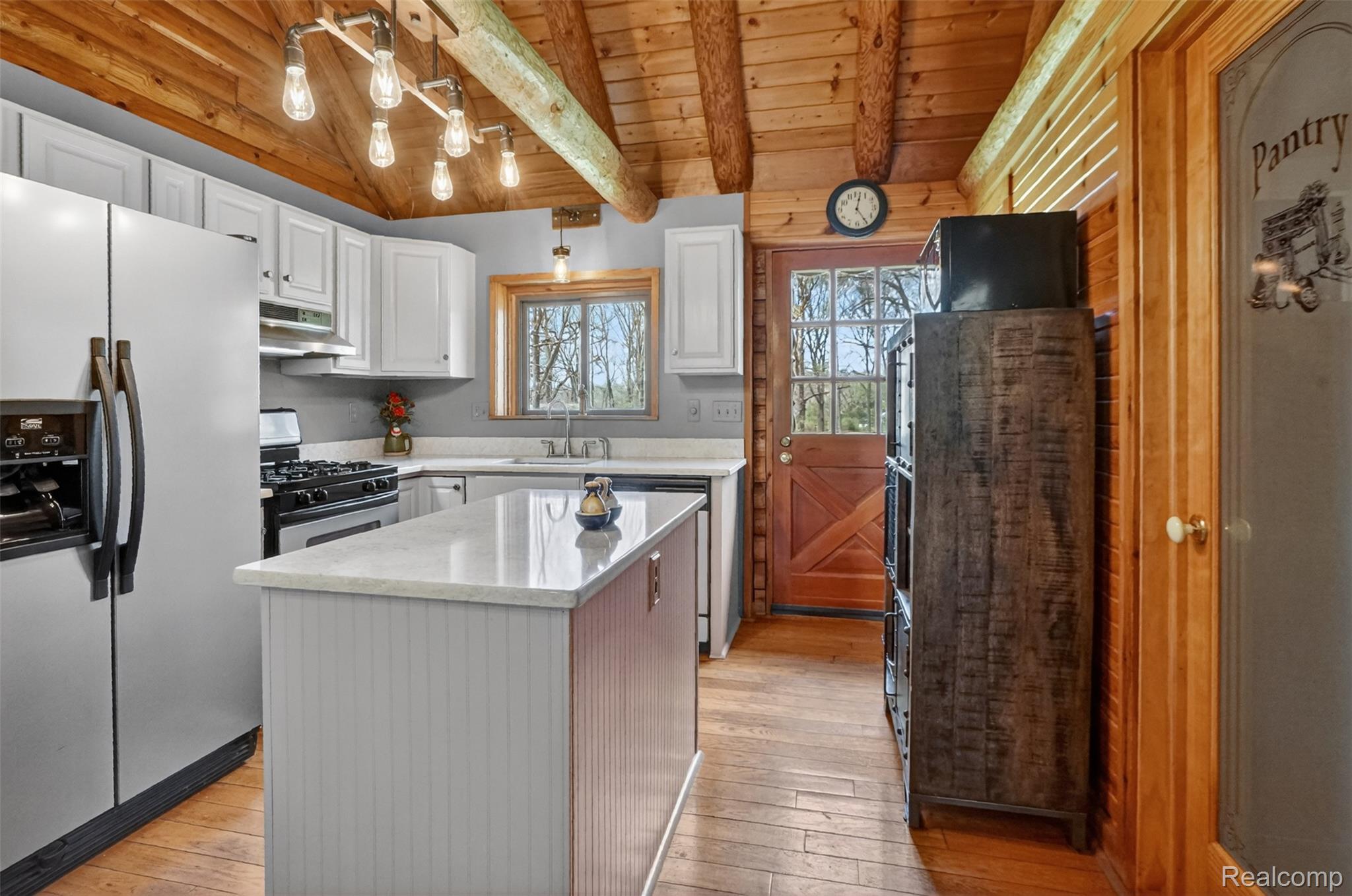 2997 Brighton Road Howell, MI 48843 - Photo 13 of 30 Kitchen featuring stainless steel appliances, wooden ceiling, a center island, white cabinetry, and vaulted ceiling with beams