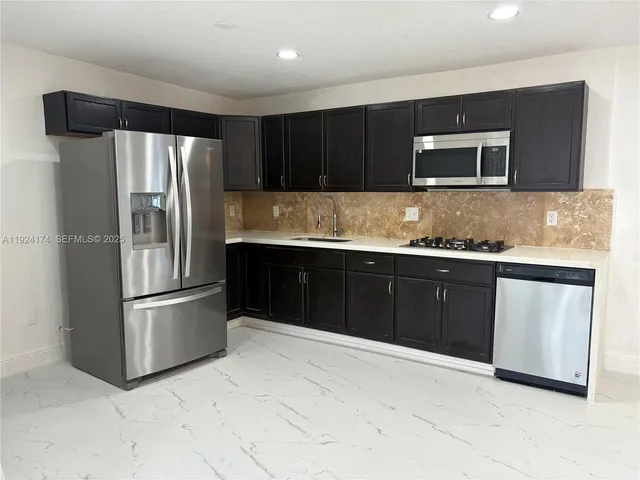 a view of kitchen with refrigerator sink and stove