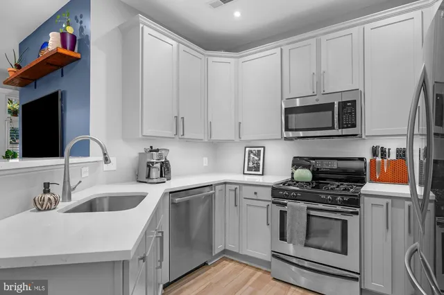 a kitchen with stainless steel appliances a stove a sink a microwave and cabinets