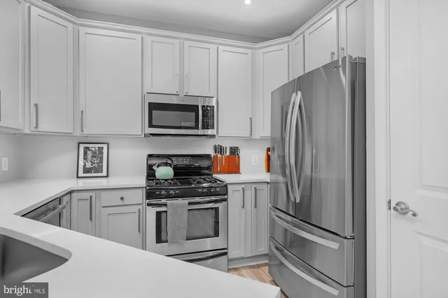 a kitchen with stainless steel appliances white cabinets white stove a microwave and a refrigerator