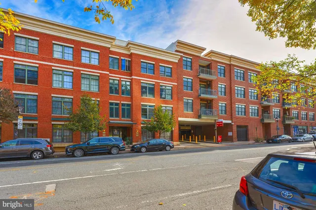 a front view of a building with lot of cars and trees