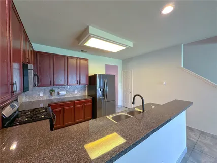 a kitchen with granite countertop stainless steel appliances a refrigerator a stove top oven and cabinets