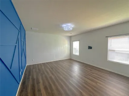 an empty room with wooden floor fireplace and windows