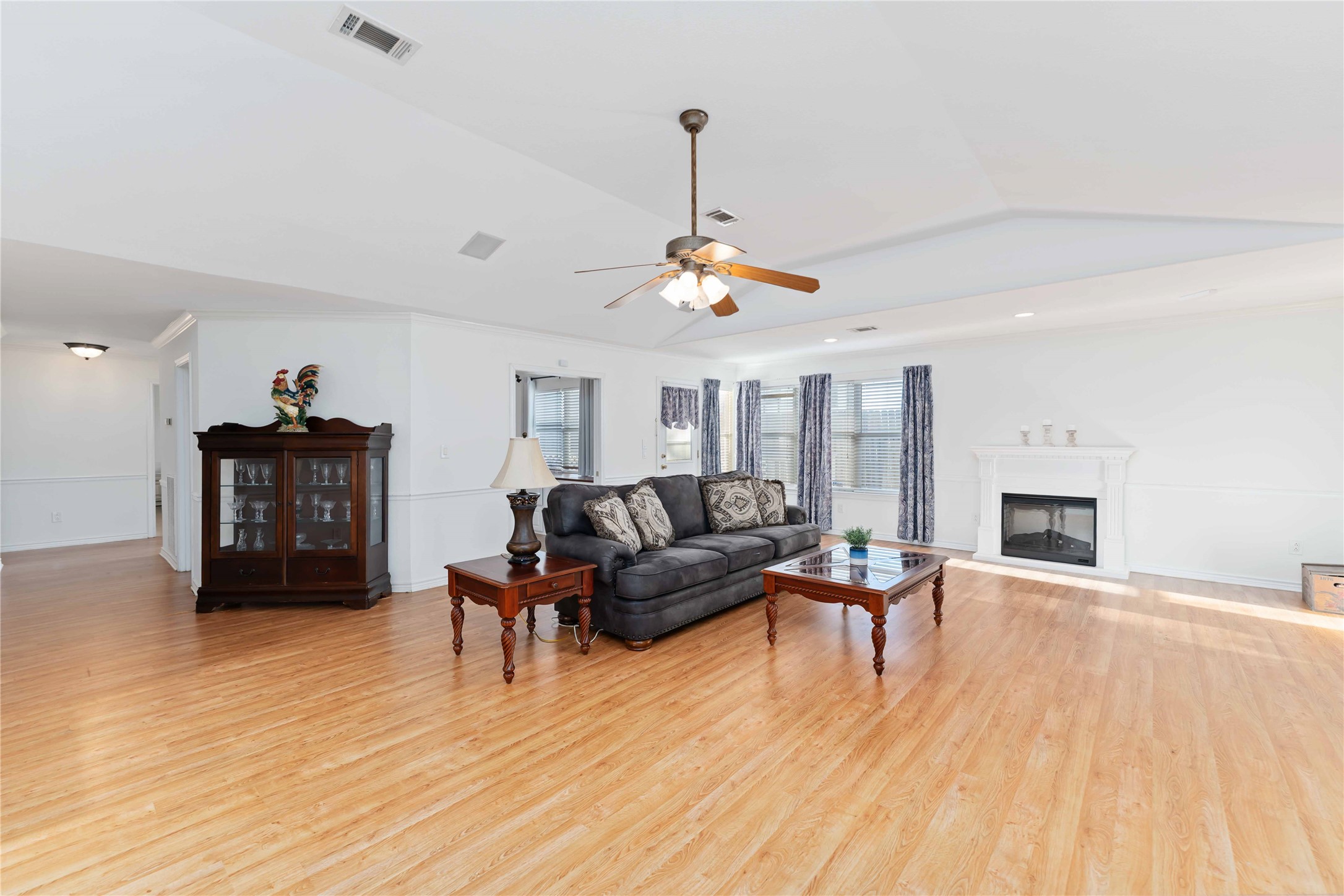 606 Packer Court Webster, TX 77598 - Photo 22 of 28 Spacious living room with hardwood floors, a cozy fireplace, ceiling fan, and ample natural light. Features a comfortable seating area and elegant decor.