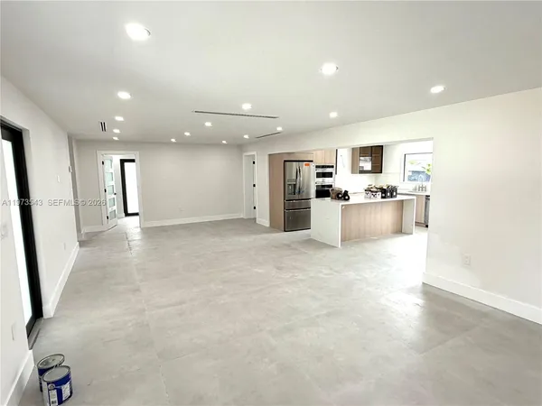 a large kitchen with stainless steel appliances a large counter top and a refrigerator