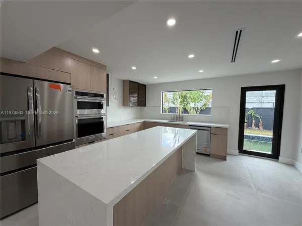 a large kitchen with a large counter top stainless steel appliances and cabinets