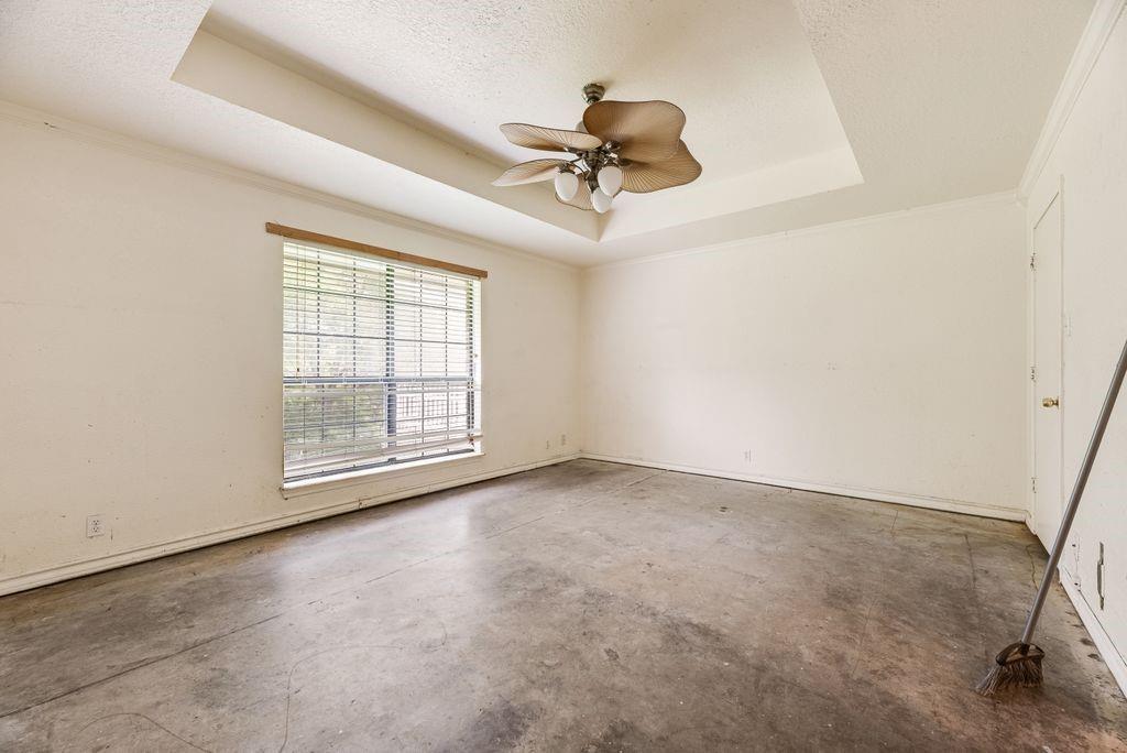298 Butterfield Road Denison, TX 75021 - Photo 8 of 34 Tray ceiling with a ceiling fan light fixture, a large window with blinds, and concrete flooring